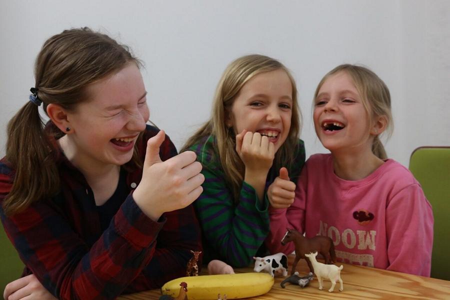 Drei Schul- und Kitakinder lachen gemeinsam